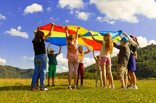 Kinder mit Schwungtuch auf einer Wiese